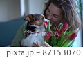 Portrait of a beautiful curly adult woman with a bouquet of red tulips hugging her pet dog. Birthday girl or mother's day concept 87153070