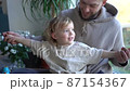 Happy cheerful caucasian man hugging his small cute son and laughing at home. Joyful parent with little kid in living room. Young father smiling and embracing child indoor. Fathers day 87154367