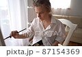 Portrait of inspired successful young artist standing on background of drawing with laptop and looking at camera smiling. 87154369