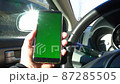 Green screen of smart phone in hand of driver in sunny city in slow motion 87285505