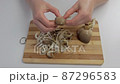 Close-up of female hands on a chopping board separating fresh mushrooms into fibers 87296583