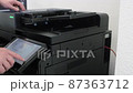 Young man in black shirt copies documents on a copying system in office 87363712