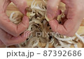 Close-up of a woman's hands dividing fresh mushrooms into fibers and throwing them into dishes 87392686