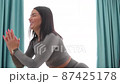 Young sporty woman glutes squats workout morning routine in living room 87425178
