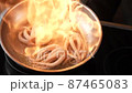 Preparing exotic fresh octopuses in metal frying pan with burning oil. Chef cooking squid tentacles in wok with orange flame in slow motion at kitchen. Asian, oriental seafood restaurant menu concept 87465083