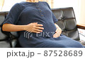 リビングでお腹をさする妊婦 87528689