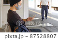 駅のホームでスマートフォンを操作する日本人男性 87528807