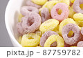 Sliding panoramic front view of milk flow pouring into white bowl with colorful cereal rings 87759782