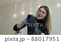 A beautiful young woman brushes her shoes before going to work. Shoe care at home 88017951