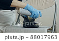 Painting and restoration of shoes at home. Close-up of a woman's hands in gloves, takes care of her shoes, sprays paint on shoes, changing its color 88017963