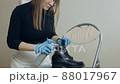 Woman spraying cleaning liquid on her shoes. Proper shoe care 88017967