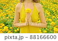 A woman holding a marigold flower at her chest. 88166600
