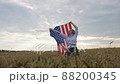 Happy patriotic young woman waves the US flag into the field 88200345