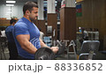Young man works out in the gym. Serious, focused. Shakes his arms, pushes the barbell 88336852