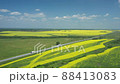 Aerial shot of many cars and truck with cargo trailer driving on road. Flying over delivery lorry moving along highway passing near fields in countryside. Scenic nature scene. 88413083
