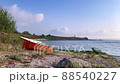 Red boat on the shore, waves on the seawater, and clouds in the morning sky. 88540227