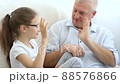 Indoor portrait of grey-haired father and little blonde girl playing with each other at home, father's day concept. 88576866