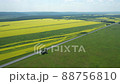 Aerial flying over asphalted intercity speed highway passing through green and yellow rural fields background on summer morning. Trucks drive along the road delivering cargo and many cars 88756810