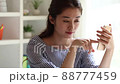 A young woman watching the internet on her smartphone indoors 88777459