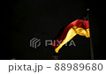 German flag flying on the wind at night. Waving flag of Germany on flagpole against dark sky. Deutschland. Black, red and yellow colors on German flag in a front of Bundestag in Berlin. 88989680