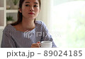 A young woman relaxing with a cup of coffee in the room 89024185