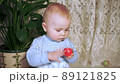 serious baby shakes small ball in her hand and then takes it in her mouth 89121825