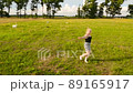 Attractive young woman runs across a large green field in summer sunny day 89165917