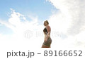 Beautiful young woman runs across a green field and spins against the background of blue clouds 89166652