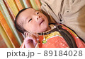 A 0 month old baby is hugged by his father on a hammock 89184028