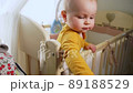 baby stands in crib and pulls her hand to camera 89188529