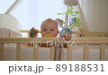 baby woke up and looks out of crib then gets up and looks at camera 89188531