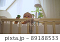 baby just woke up and looks out of crib holding pacifier 89188533