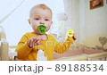 baby woke up and stands in crib, holding pacifier 89188534