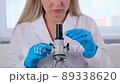Female scientist laboratory assistant looks at a petri dish with genetically modified samples of 89338620