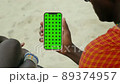 Masai Tribe Men Looking at the Smartphone and Touching Green Screen in the Front of Desert 89374957