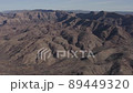 Panoramic, drone view, panning right, high above an expansive mountain range, with steep ravines, in an arid climate 89449320