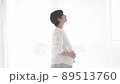 Pregnant woman standing by the window with a smile 89513760