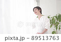 Pregnant woman standing by the window with a smile 89513763