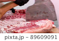 The butcher chops raw pork meat with sharp axe at meat processing plant. 89609091