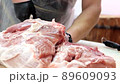 The butcher carves bones from pork body at meat processing plant. 89609093
