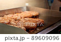 The chef lays out the sausages on the electric grill, close-up 89609096