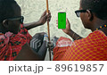 Masai Tribe Men Looking at the Smartphone Green Screen in the Front of Desert 89619857