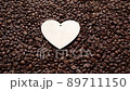 Man puts wooden heart on roasted coffee beans. Top view. Coffee love concept. 89711150