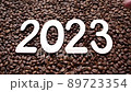 Numbers 2023 on the background of roasted coffee beans. New Year. Top view. Man puts the number 3. Mary christmas. 89723354