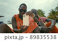 Happy Maasai Tribe Men Sitting on the Sand in the Desert and Looking at the Smartphone. 89835538