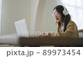 Young asian woman wearing glasses and headset working on computer laptop at house 89973454