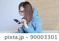 Woman sits on the sofa and reading messages using smartphone  90003301