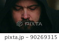A man with a beard in the hood looks sadly down after at the camera, static camera, close-up of the face 90269315