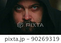 A man with a beard in the hood looks sadly at the camera and touches his beard, static camera, close-up of the face 90269319