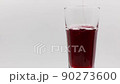 Pour pomegranate juice into a rotating glass on a white background. 90273600